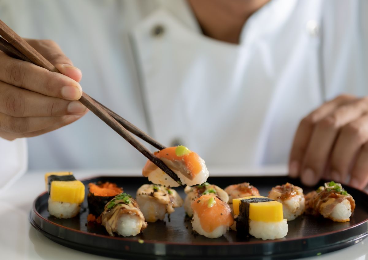 Mann nimmt Sushi mit Stäbchen von einem schönen Sushi-Teller