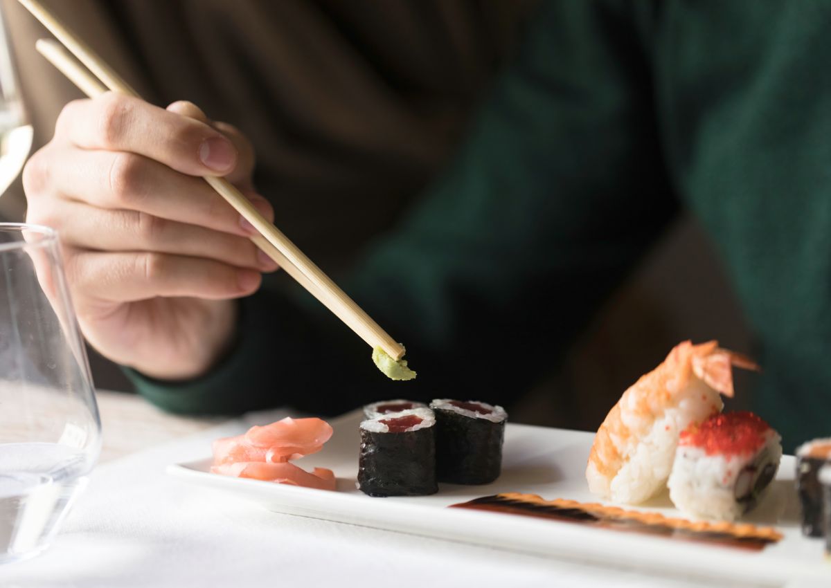 Person hält mit Essstäbchen ein Stück Wasabi