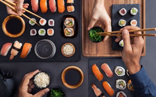Verschiedene Sushi wie Nigiri, Sashimi und Rollen werden geteilt und mit Stäbchen gegessen