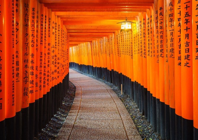 Ein traditionelles rotes Torii mit schwarzer Schrift im Fushimi-Inari-Schrein in Kyōto, Japan