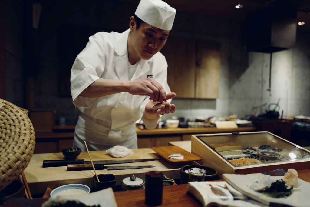 Japanischer Chefkoch macht Sashimi vor der Theke eines japanischen Sushi-Restaurants
