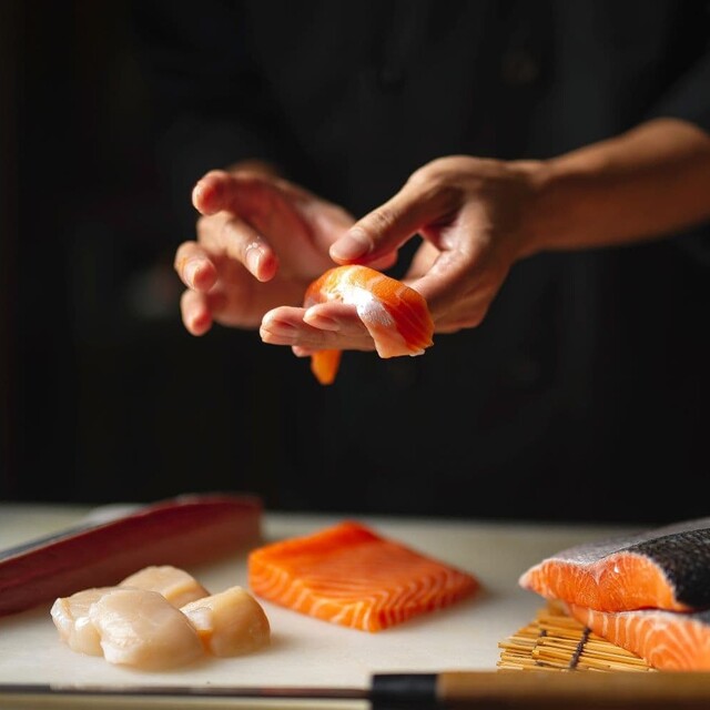 Hände, die Sushi zubereiten